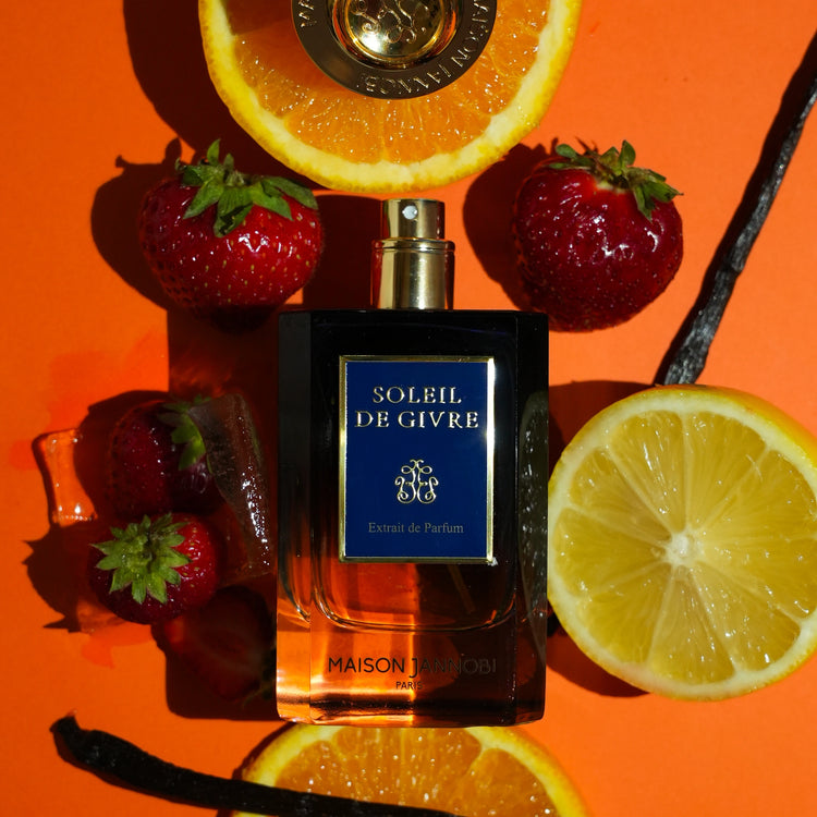 MAISON JANNOBI — le flacon Soleil de Givre entouré d'oranges, de fraises des bois et de gousses de vanille, univers solaire de la maison de parfumerie française