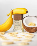 THEODOROS KALOTINIS Banane de Coco Extrait de Parfum 50 ml — mise en scène du flacon entre bananes mûres et noix de coco ouverte, gourmand lacté, parfum niche de Grèce