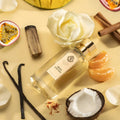LES NOBLES ESSENCES Mirage Exotique Extrait de Parfum 100 ml — flacon entouré de mangue, fruit de la passion, noix de coco, mandarine, rose et safran