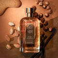 LES NOBLES ESSENCES Mirage Gourmand Extrait de Parfum — flacon entouré de noisettes, pistaches, amandes et gousses de vanille, les matières du parfum