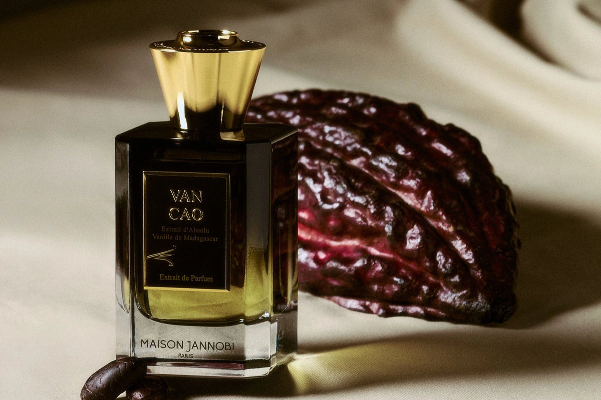 MAISON JANNOBI — le flacon Van Cao posé sur un drapé de soie, devant une cabosse de cacao